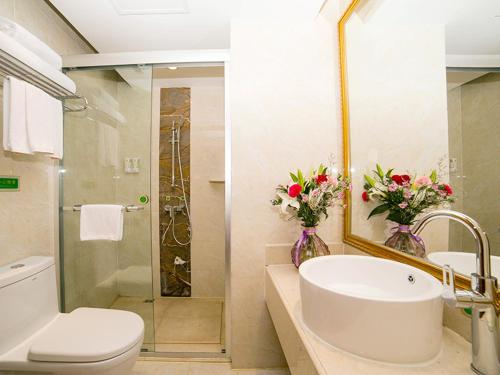 a bathroom with a sink and a toilet and a shower at Vienna Hotel Shandong Yantao Golden Beach Taishan Road in Yantai