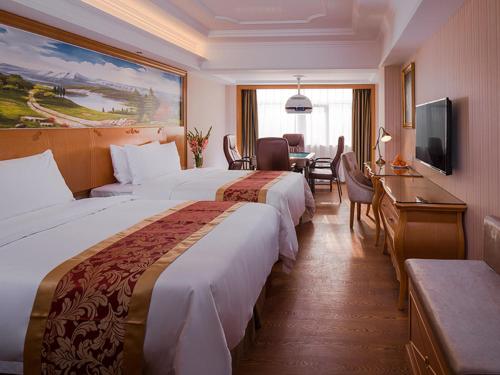 Fenghuangwei的住宿－维也纳国际酒店 (深圳福永会展中心店)，酒店客房设有两张床、一张桌子和电视。