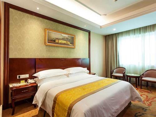 Cette chambre comprend un grand lit et une fenêtre. dans l'établissement Vienna Hotel Nanjing Longjiang, à Nankin