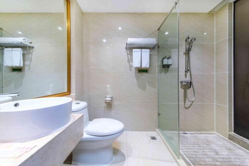 a bathroom with a toilet and a glass shower at Vienna Hotel Shenzhen Bantian Gangtou in Tiantangwei