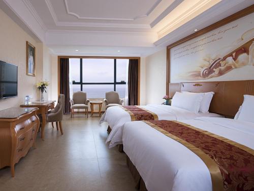 a hotel room with two beds and a table and chairs at Vienna International Hotel Guangdong Yangjiang Zapo Travel Avenue in Lizao