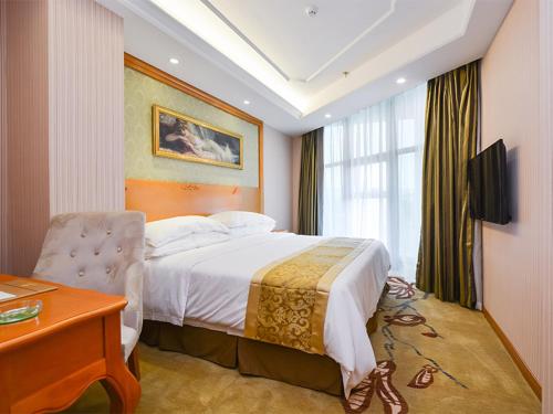 南京市にあるVienna Hotel Nanjing Pukou Middle Puzhu Roadのベッドとデスクが備わるホテルルームです。