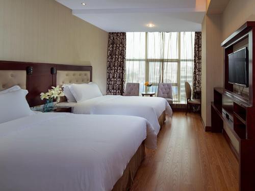 LonggangにあるVienna Hotel in Pinghu Squareのベッド2台、薄型テレビが備わるホテルルームです。