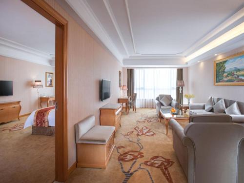 - un salon avec un canapé et un lit dans une chambre d'hôtel dans l'établissement Vienna Hotel Dongguan Shi, à Dongguan