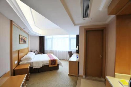 a hotel room with a bed and a bathroom at Vienna Hotel Qidong South Gongyuan Road in Qidong