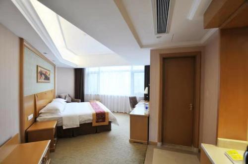 a hotel room with a bed and a bathroom at Vienna Hotel Qidong South Gongyuan Road in Qidong