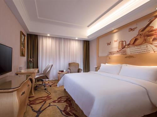 a hotel room with a large white bed and a television at Vienna Hotel Shenzhen North Science And Technology Park in Shenzhen