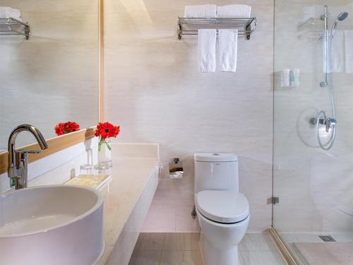 a white bathroom with a toilet and a shower at Vienna International Hotel - Long Hua Wan Zhong Cheng Branch in Bao'an