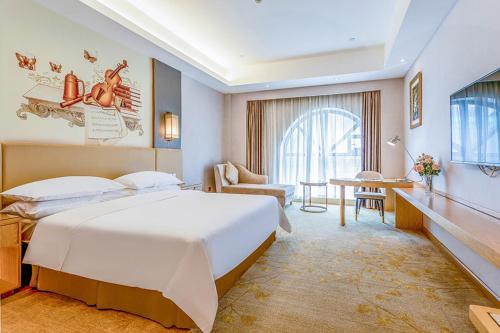 een hotelkamer met een groot bed en een bureau bij Vienna International Hotel Guangdong Zhengjiang Renming Avenue Middle Road in Zhanjiang