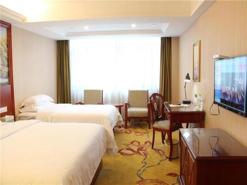 a hotel room with two beds and a flat screen tv at Vienna International Hotel Ningbo South Huancheng Road in Ningbo