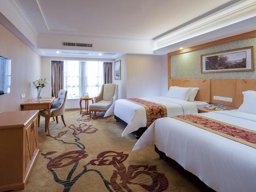 a hotel room with two beds and a desk at Vienna International Hotel Zhongshan Torch Development Zone in Zhongshan
