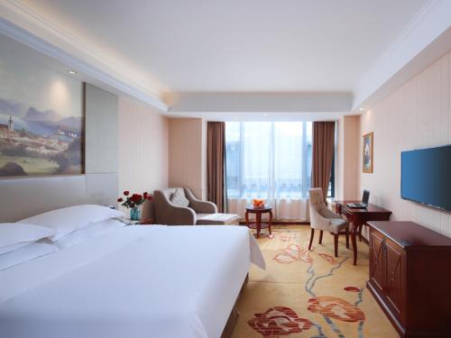 a hotel room with a large bed and a living room at Vienna Hotel Suzhou Mudu Changjiang No 1 in Suzhou