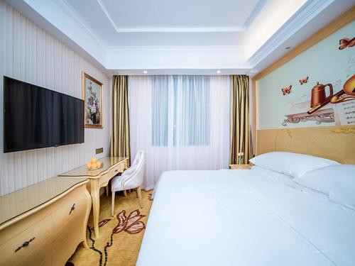 a hotel room with a large bed and a desk at vienna hotel (HuaZhong Agricultural University in South Lake Store) in Wuhan
