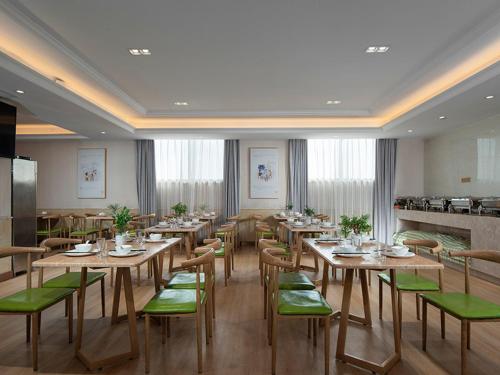 un comedor con mesas de madera y sillas verdes en Vienna Hotel (Dongmin Road Nanning) en Nanning