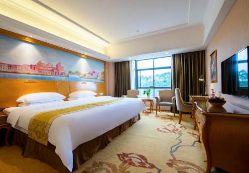 um quarto de hotel com uma cama grande e uma secretária em Vienna Hotel Qinzhou North Area Plaza em Qinzhou