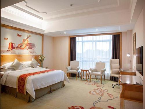 een hotelkamer met een groot bed en een bureau bij Vienna Hotel Ganzhou Anyuan in Tieshan