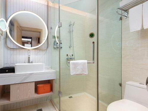 uma casa de banho com um chuveiro, um lavatório e um espelho. em Vienna International Hotel Changsha Furong Plaza em Changsha
