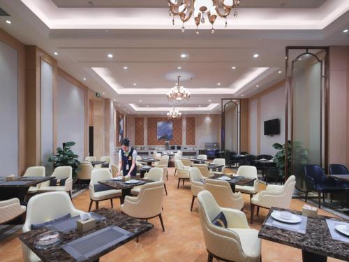 Un hombre de pie en una habitación con mesas y sillas. en Vienna International Hotel Changsha West Bus Station, en Changsha