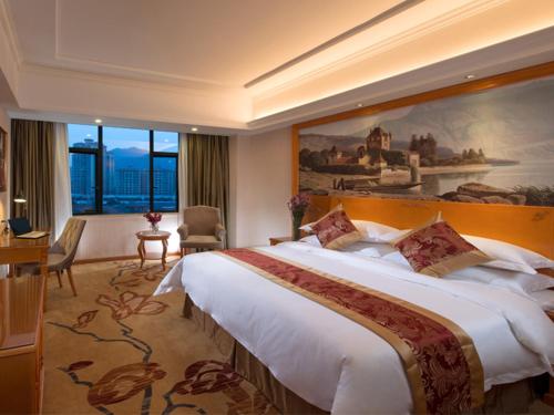 a hotel room with a large bed and a large painting at Vienna Classic Hotel Foshan Nanhai Xijiao in Nanhai