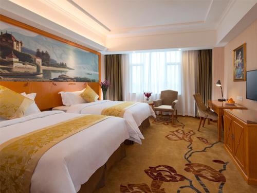 a hotel room with two beds and a desk at Vienna Classic Hotel Foshan Nanhai Xijiao in Nanhai