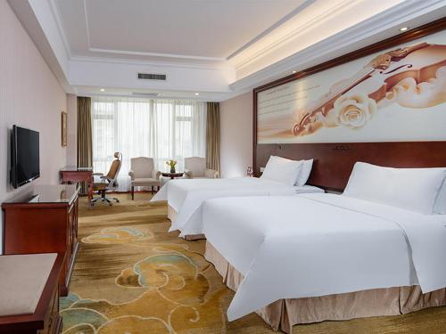 Habitación de hotel con 2 camas y TV de pantalla plana. en Vienna Hotel Foshan Huangqi, en Nanhai