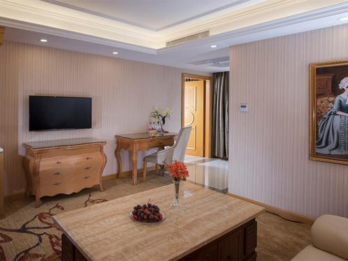 a living room with a television and a table at Vienna Hotel(Shenzhen Shajing Jingjinbaina Branch) in Shenzhen