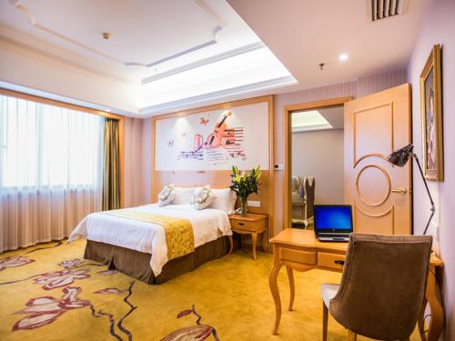 um quarto com uma cama, uma secretária e um computador portátil em Vienna Hotel Hunan Shaodong Jinlong Ave em Shaodong