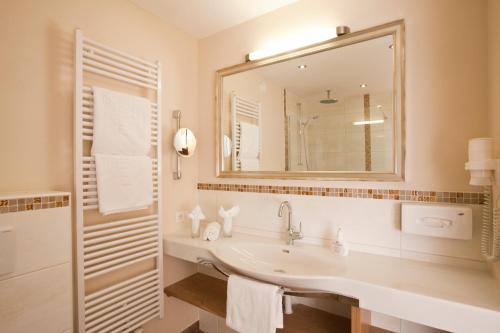 a white bathroom with a sink and a mirror at Seehotel Brunner in Walchsee