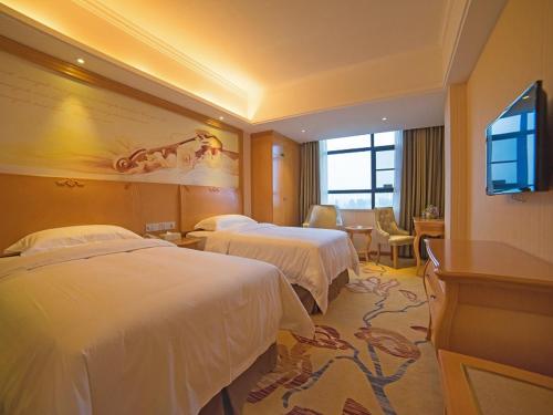 una camera d'albergo con due letti e una televisione di Vienna 3 Best Hotel Luoding Chuangyue Building a Shuangdongjieban