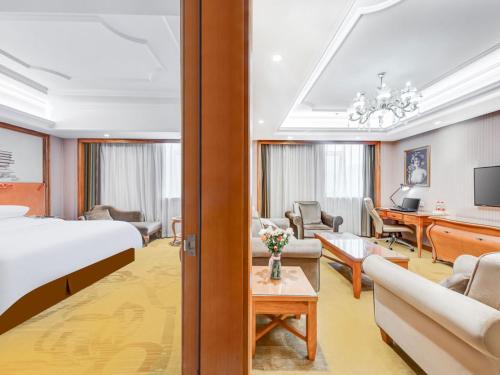 a hotel room with a bed and a living room at Vienna Hotel Wuhan Yellow Crane Tower in Wuhan