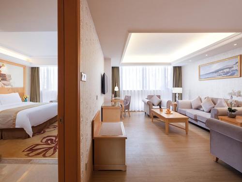 a hotel room with a bed and a living room at Vienna Hotel Zhongshan West District in Zhongshan
