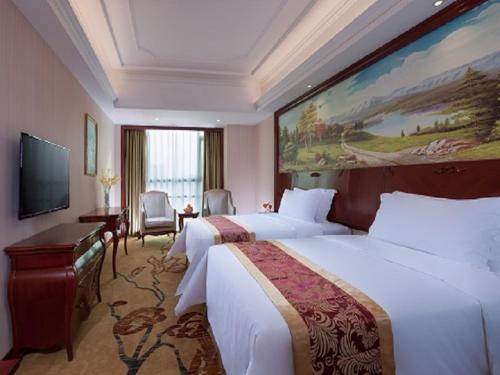 a hotel room with two beds and a large painting on the wall at Vienna International Hotel Heyuan Yajule Garden in Heyuan