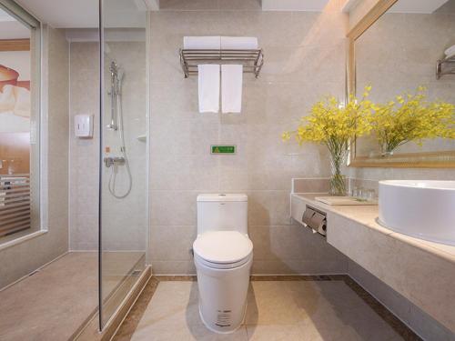 a bathroom with a toilet and a sink and a shower at Vienna International Hotel Foshan Beijiao New City Meidi Headquarter in Shunde