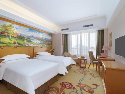 a hotel room with three beds and a flat screen tv at Vienna Hotel Shandong Qingdao Chengyang in Xifu