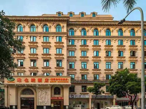 a large tan building with blue windows on a street at Vienna Hotel Zhuhai Xiangzhou Bus Station in Zhuhai