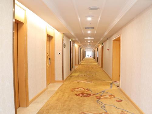 un couloir d'un immeuble de bureaux avec un couloir recouvert de moquette dans l'établissement Vienna International Hotel Changsha Lugu, à Changsha
