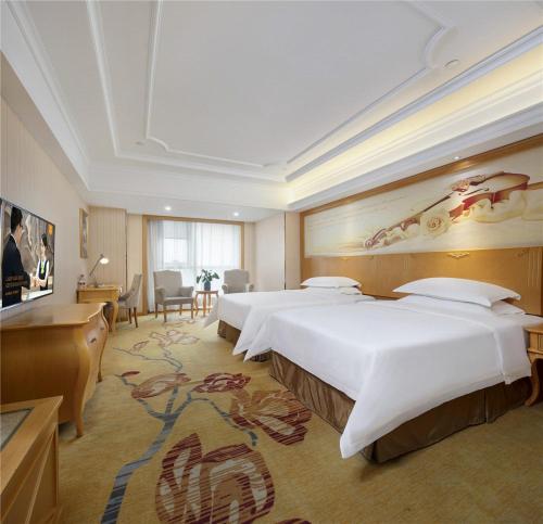 a large hotel room with two beds and a desk at Vienna Hotel Zhengzhou Zhongyuan Futa in Zhengzhou