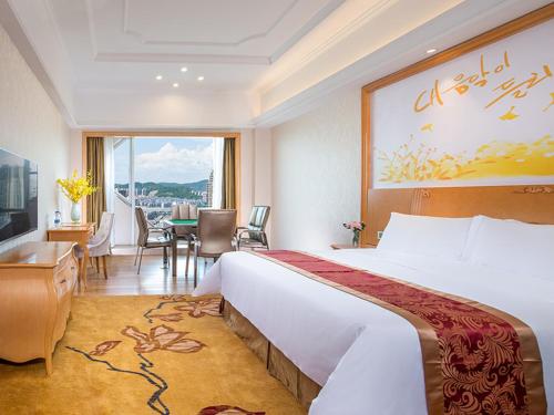 a hotel room with a large bed and a table at Vienna International Hotel Hunan Chenzhou Qingnian Avenue in Chenzhou