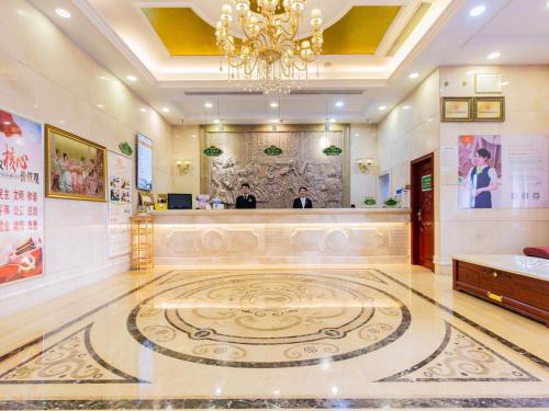 a hotel lobby with a reception desk and a chandelier at Vienna Hotel CHangsha Bayi Bridge Hefu in Changsha