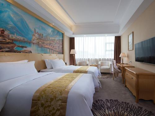 a hotel room with two beds and a large painting at Vienna Hotel Guangzhou Baiyun Airport in Guangzhou