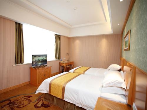 a hotel room with a bed and a television at Vienna Hotel Jiangsu Kunshan Exhibition Center in Kunshan