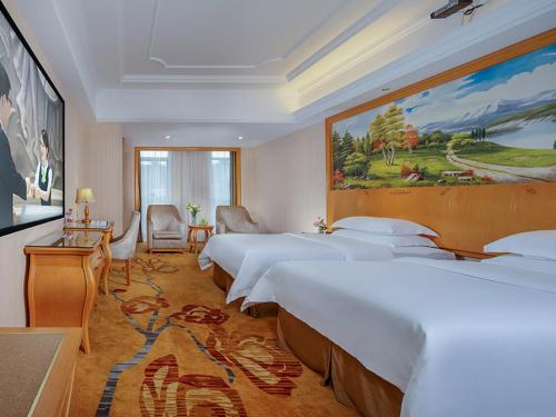 a room with four beds and a painting on the wall at Vienna Hotel Chengdu Wenjiang Zhujiang Plaza in Wenjiang