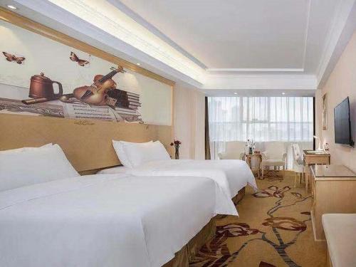 um quarto de hotel com duas camas e uma televisão em Vienna Hotel Huizhou Railway Station em Huizhou