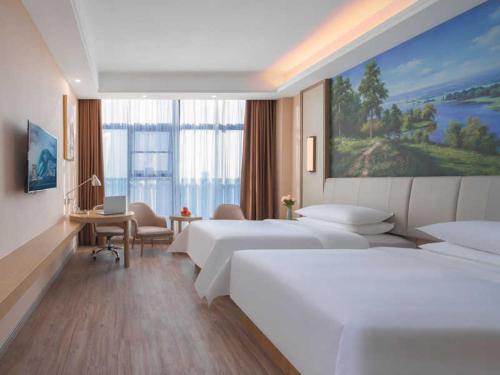 a hotel room with two beds and a desk with a computer at Vienna Hotel Hangzhou Yuhang Linping in Yuhang