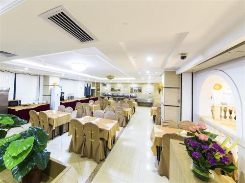 Vienna Hotel Zhanjiang Coast Avenue في زانجيانغ: مطعم فيه طاولات وكراسي في الغرفة