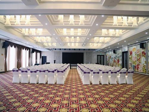 a banquet hall with rows of chairs and a screen at Vienna Hotel Yinchuan Railway Station in Yinchuan