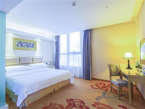 a hotel room with a large bed and a desk and a desk at Vienna Hotel Zhanjiang Coast Avenue in Zhanjiang