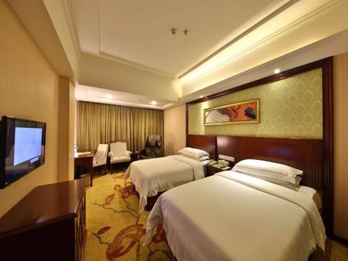 a hotel room with two beds and a flat screen tv at Vienna Hotel Zhangjiajie North Railway Station in Zhangjiajie