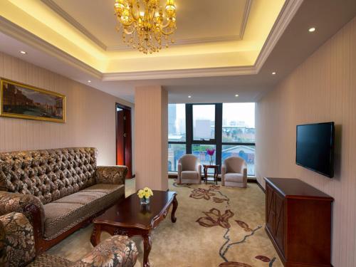 a living room with a couch and a television at Vienna Hotel Shunde Longjia Exhibition Center in Shunde
