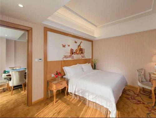 a bedroom with a large white bed and a desk at Vienna Hotel Shenzhen Baoneng City Plaza in Longgang